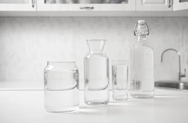 瓶装水 白桌子上装满透明玻璃杯 厨房内部 纯净水 清澈的水A — 图库照片