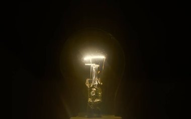 İlham verici bir kavram olarak parlayan sarı ampul. Siyah arkaplanda bir ampul izole edildi.         