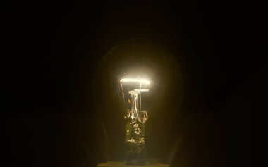 İlham verici bir kavram olarak parlayan sarı ampul. Siyah arkaplanda bir ampul izole edildi.         