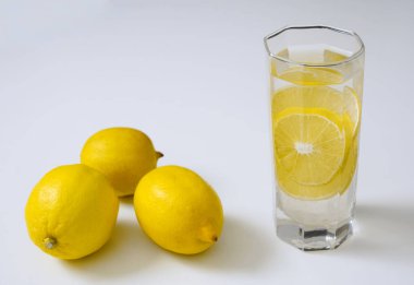 Saf içme suyu ve beyaz masada şeffaf bir bardakta üç limon. Yan görünüş. beyaz arkaplanda izole. 