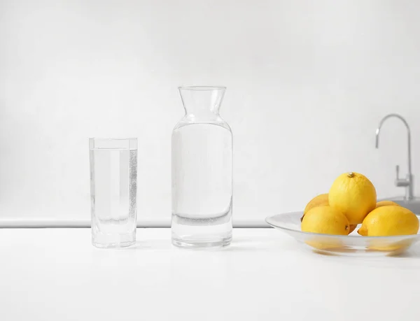 Φρέσκα Λεμόνια Και Γυάλινο Μπουκάλι Καθαρό Νερό Στέκεται Ξύλινο Τραπέζι — Φωτογραφία Αρχείου