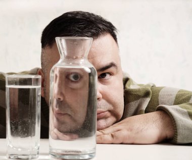 surreal portrait of a strange man looking through glasses of water. man looking through glass glasses of water with reflections and distortions. isolated on white background.
