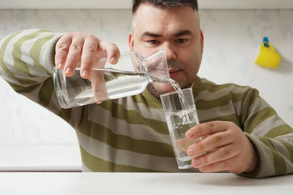 Middle Aged Man Pouring Water Bottle Glass Background Kitchen Interior — Stock fotografie