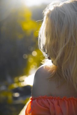 Parktaki bulanık yaz ağaçlarının arka planında yaşayan güzel bir kız.