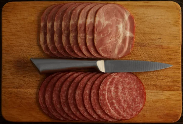 Aufgeschnittene Salami Eisernes Messer Und Schneidebrett Isoliert Auf Schwarzem Holztischhintergrund — Stockfoto