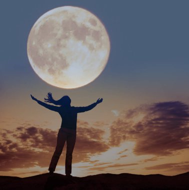 Dalgaya ve dolunaya bakan ellerini kaldırmış bir kadının silüeti..