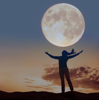 Dalgaya ve dolunaya bakan ellerini kaldırmış bir kadının silüeti..