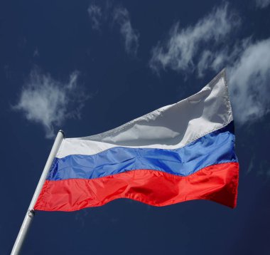 Mavi gökyüzüne karşı rüzgarda dalgalanan üç renkli Rus bayrağı. Mavi bulutlu arkaplanda Rus bayrağı