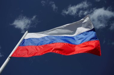 Mavi gökyüzüne karşı rüzgarda dalgalanan üç renkli Rus bayrağı. Mavi bulutlu arkaplanda Rus bayrağı