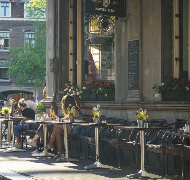 Amsterdam, Hollanda - 22 Temmuz 2019: Amsterdam Kafe 'nin dışındaki bir terasta oturan bilinmeyen insanlar. Şehirde 1500 'den fazla bar ve kafe var.