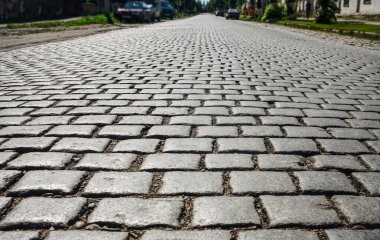 Yürümek için kaldırım taşı arka planı. Güneş ışığında kaldırım taşı sokağında granit bloklardan yapılmış bir duvar var. Kalininingrad bölgesi. 