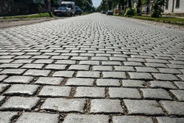Yürümek için kaldırım taşı arka planı. Güneş ışığında kaldırım taşı sokağında granit bloklardan yapılmış bir duvar var. Kalininingrad bölgesi. 