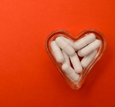 Lityum orotat kapsüllerine yakın çekim. Beslenme konsepti. Kalp şeklinde dolu gözlük kasesi. Beslenme takviyesi, üst görünüm