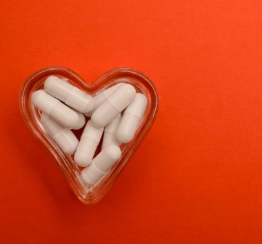 Lityum orotat kapsüllerine yakın çekim. Beslenme konsepti. Kalp şeklinde dolu gözlük kasesi. Beslenme takviyesi, üst görünüm
