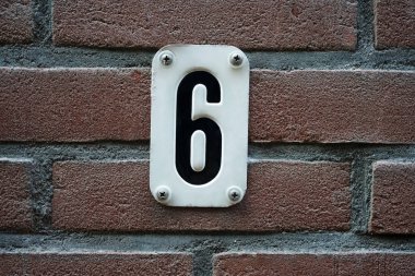 Hollanda Amsterdam 'daki 6 numaralı evi kapatın. 6 numaralı ev kırmızı tuğlalı duvarda, 6 numaralı beyaz metal plakalı.