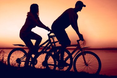 İki kişi bisiklette oturuyor. günbatımı bulutlu gökyüzü arkaplanı. 