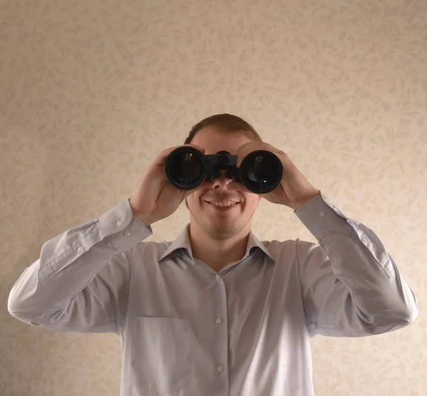 Jonge Zakenman Kijkt Door Een Verrekijker Tegen Een Grijze Muur — Stockfoto