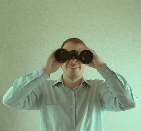 Jonge Zakenman Kijkt Door Een Verrekijker Tegen Een Grijze Muur — Stockfoto