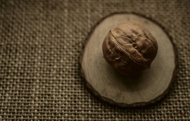 Kahverengi bir çuval bezi üzerinde yuvarlak ceviz. Çuval bezinde kabuklu ceviz.