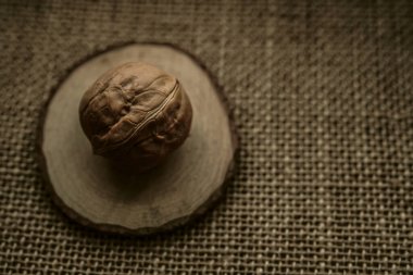 Kahverengi bir çuval bezi üzerinde yuvarlak ceviz. Çuval bezinde kabuklu ceviz.