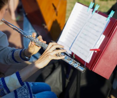 Kız büyük bir konser flütü tutuyor (yakın plan). Provadaki profesyonel müzisyen. Bir kadın enine flüt çalıyor. Flüt çalan bir müzisyenin ellerinin yakın çekimi.