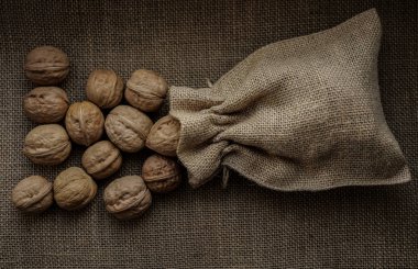 Kalıplı bir arka planda, çuval bezin içinde ceviz. Çuval içinde fındık.. 