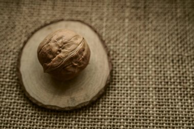 Kahverengi bir çuval bezi üzerinde yuvarlak ceviz. Çuval bezinde kabuklu ceviz.