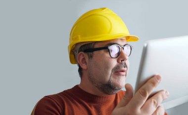 Bilgisayar tabletli sarı kasklı adam..