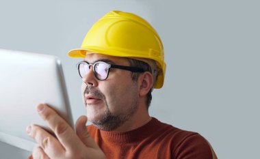 Bilgisayar tabletli sarı kasklı adam..