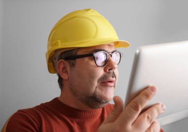 Bilgisayar tabletli sarı kasklı adam..