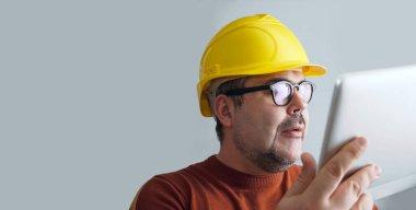 Bilgisayar tabletli sarı kasklı adam..