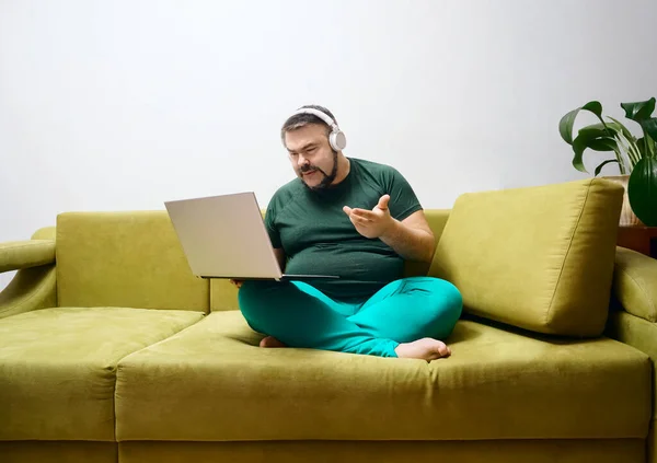 Serieuze Bebaarde Man Met Laptop Draadloze Hoofdtelefoon Casual Kleding Zitten — Stockfoto