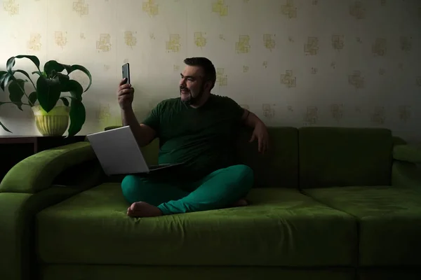 Šťastný Vousatý Muž Brunetkou Vlasy Sedí Gauči Pomocí Notebooku Mobilního — Stock fotografie