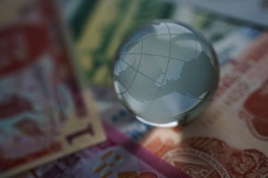 Çeşitli uluslararası para banknotlarında dünya küresi kristal bardakları. Döviz kurları. Finansal yatırım konsepti. Küresel iş ve ekonomi