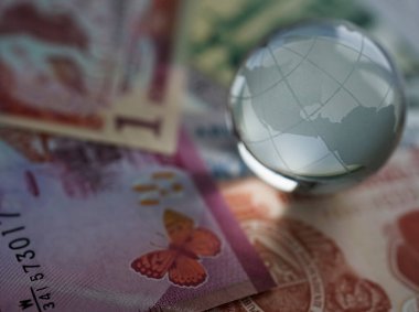 Çeşitli uluslararası para banknotlarında dünya küresi kristal bardakları. Döviz kurları. Finansal yatırım konsepti. Küresel iş ve ekonomi