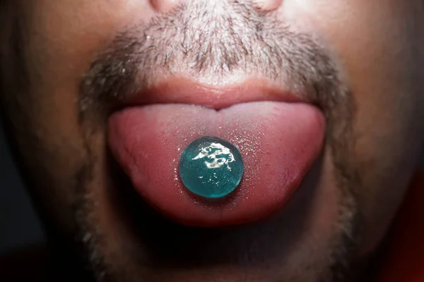 髭の男の舌の上にある喉からロリポップ 錠剤を食べる男は喉の痛みパスティーユを咳 カウドロップの男 喉を痛め 咳をしなさい — ストック写真