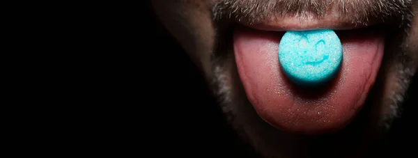 舌にキャンディ ピルの髭を生やした男 湿った舌の上に砂糖の青い塊 暗い影を持つ劇的な光 プリントスマイリーフェイス — ストック写真