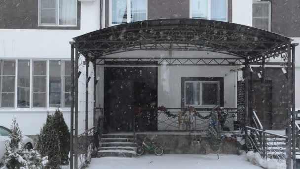 Blick aus dem Fenster auf das Nachbarhaus und fallenden Schnee — Stockvideo