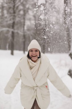 Kışın sıcak kış kıyafetleriyle karda kartopu oynayan iki kız.
