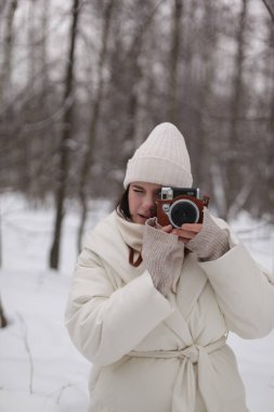 Ormanda kış yürüyüşüne çıkmış kameralı bir kız.
