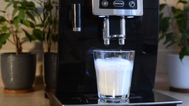Kahve makinesinde kapuçino pişirmek. Kahve toplanan köpüklü süte dökülür.