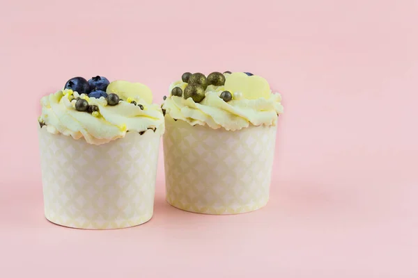 Zwei festliche Cupcakes mit Beeren und Dekor auf rosa Hintergrund Stockbild