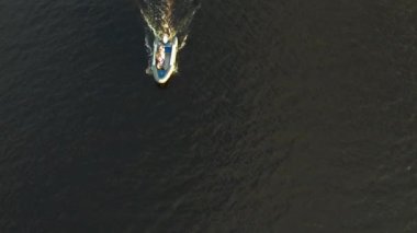 Mavi denizde yüksek hızda seyreden lüks sürat teknesinin fotokopi uzayına sahip bir hava aracı. Yelkenli yatın ve suda altın gün batımının yansıması. Okyanustaki denizcilik gemisinde boş zaman. 