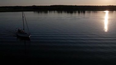 Mavi denizde yüksek hızda seyreden lüks sürat teknesinin fotokopi uzayına sahip bir hava aracı. Yelkenli yatın ve suda altın gün batımının yansıması. Okyanustaki denizcilik gemisinde boş zaman. 
