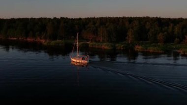 Mavi denizde yüksek hızda seyreden lüks sürat teknesinin fotokopi uzayına sahip bir hava aracı. Yelkenli yatın ve suda altın gün batımının yansıması. Okyanustaki denizcilik gemisinde boş zaman. 