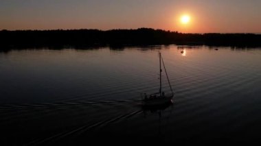 Mavi denizde yüksek hızda seyreden lüks sürat teknesinin fotokopi uzayına sahip bir hava aracı. Yelkenli yatın ve suda altın gün batımının yansıması. Okyanustaki denizcilik gemisinde boş zaman. 
