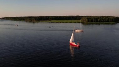 Mavi denizde yüksek hızda seyreden lüks sürat teknesinin fotokopi uzayına sahip bir hava aracı. Yelkenli yatın ve suda altın gün batımının yansıması. Okyanustaki denizcilik gemisinde boş zaman. 