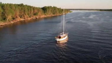 Mavi denizde yüksek hızda seyreden lüks sürat teknesinin fotokopi uzayına sahip bir hava aracı. Yelkenli yatın ve suda altın gün batımının yansıması. Okyanustaki denizcilik gemisinde boş zaman. 