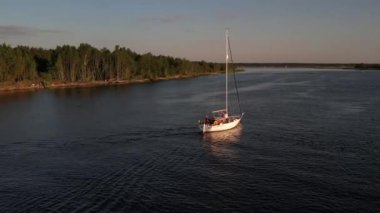 Mavi denizde yüksek hızda seyreden lüks sürat teknesinin fotokopi uzayına sahip bir hava aracı. Yelkenli yatın ve suda altın gün batımının yansıması. Okyanustaki denizcilik gemisinde boş zaman. 