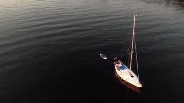 Mavi denizde yüksek hızda seyreden lüks sürat teknesinin fotokopi uzayına sahip bir hava aracı. Yelkenli yatın ve suda altın gün batımının yansıması. Okyanustaki denizcilik gemisinde boş zaman.